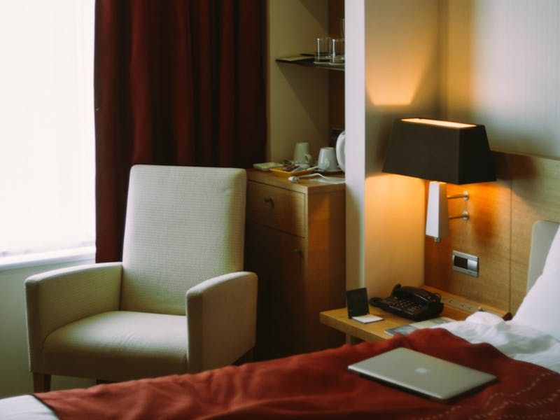 Stilvolles Hotelzimmer mit hellem Sessel und roten Gardinen