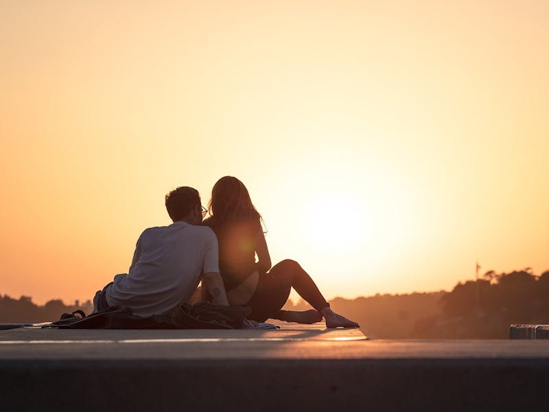 Paar sitzt draußen bei Sonnenuntergang