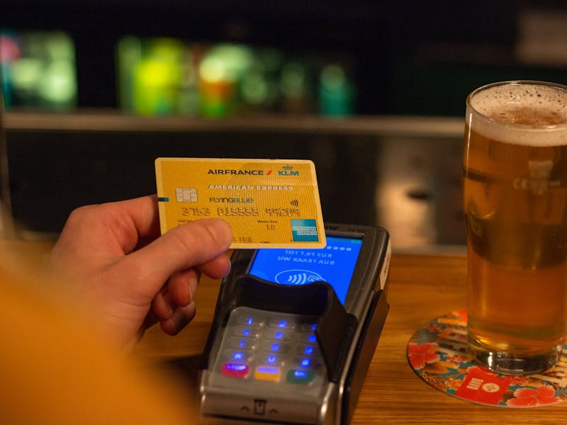 Ein Mann bezahlt in einer Kneipe Bier mit einer Amex-Karte