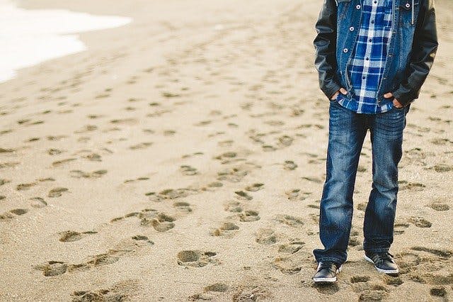 Mann in Jeans und Jeans Jacke am Strand 